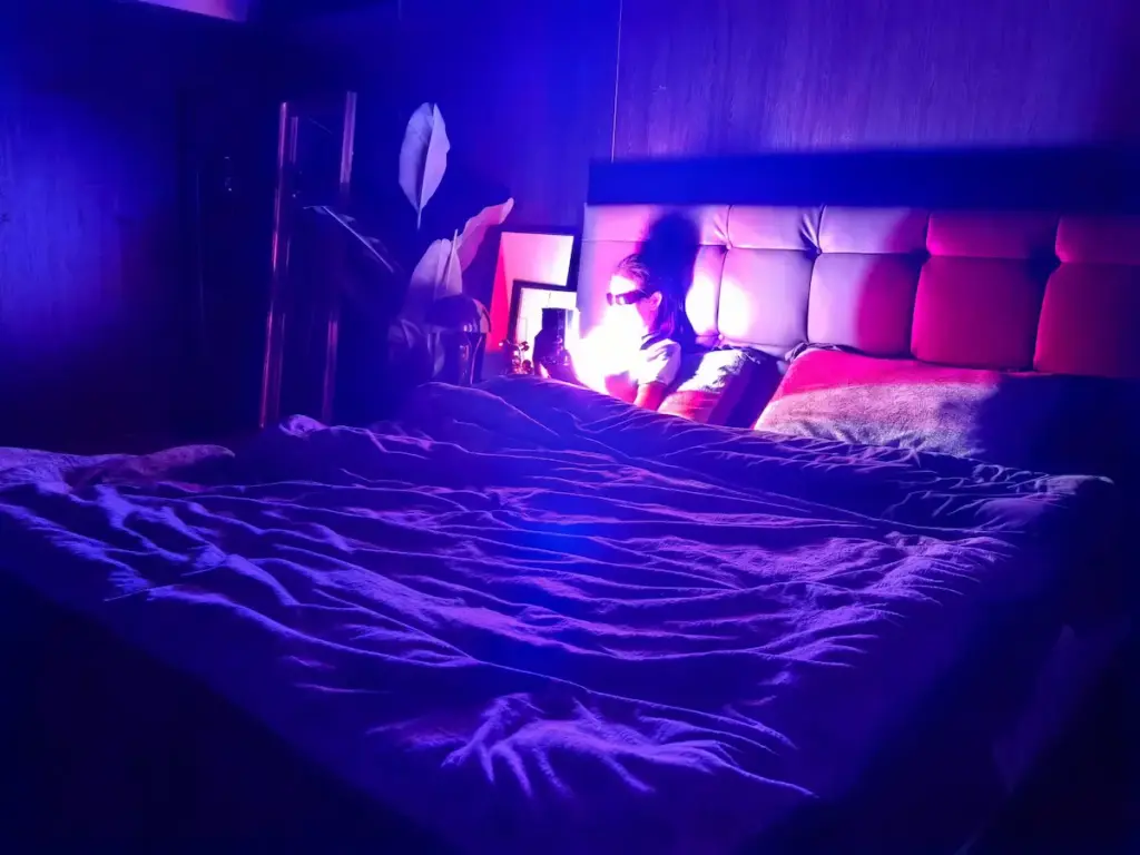 Person using Sweet Aurora ambient lamp in bedroom (eyewear as personal comfort choice)